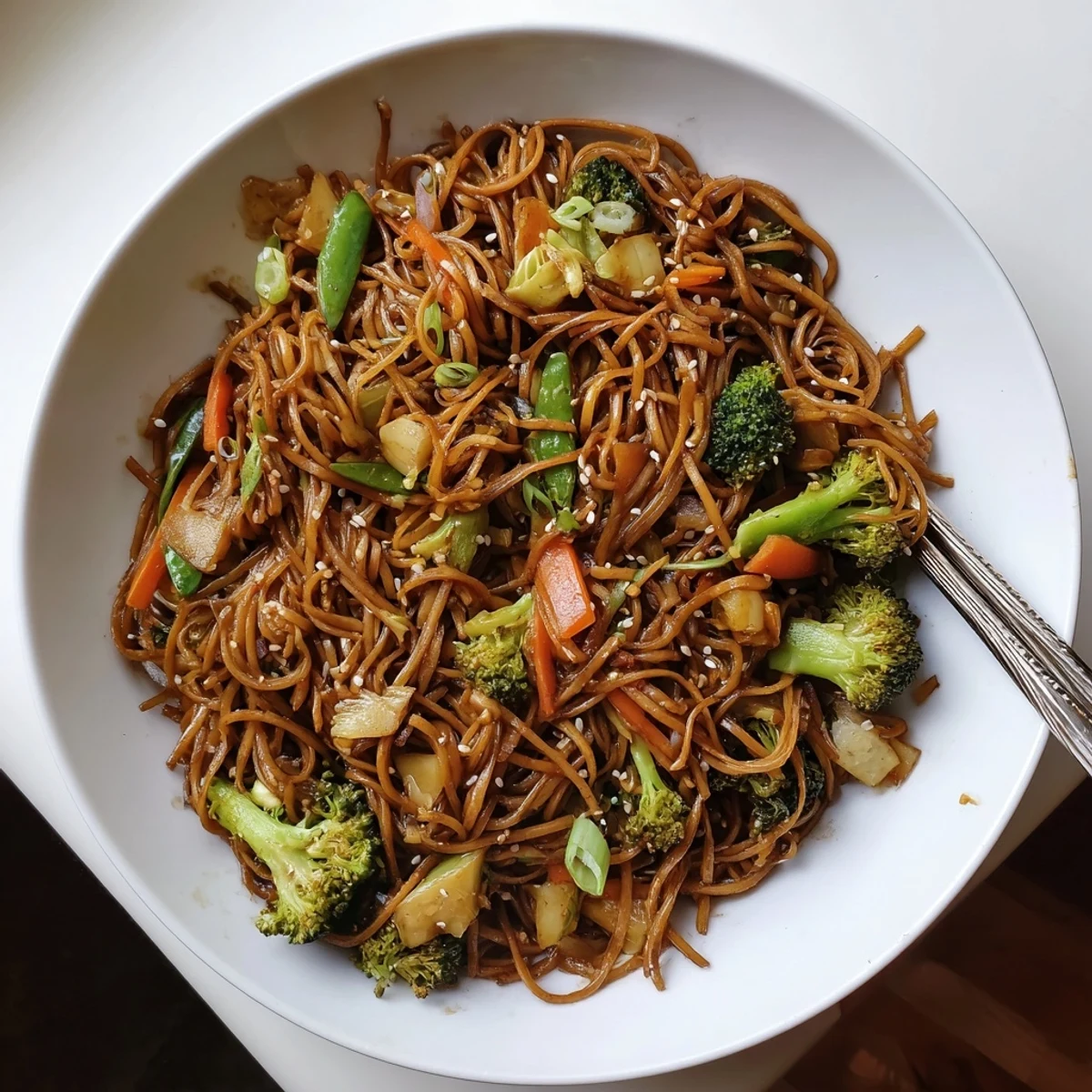 A colorful veggie stir-fry noodles dish topped with fresh herbs and sesame seeds.  
