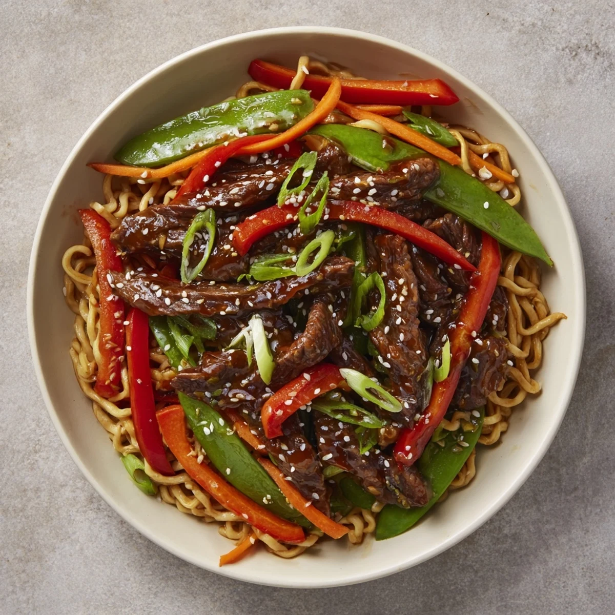 Steaming Teriyaki Beef & Noodle Bowl with glistening sauce, topped with sesame seeds and green onions.