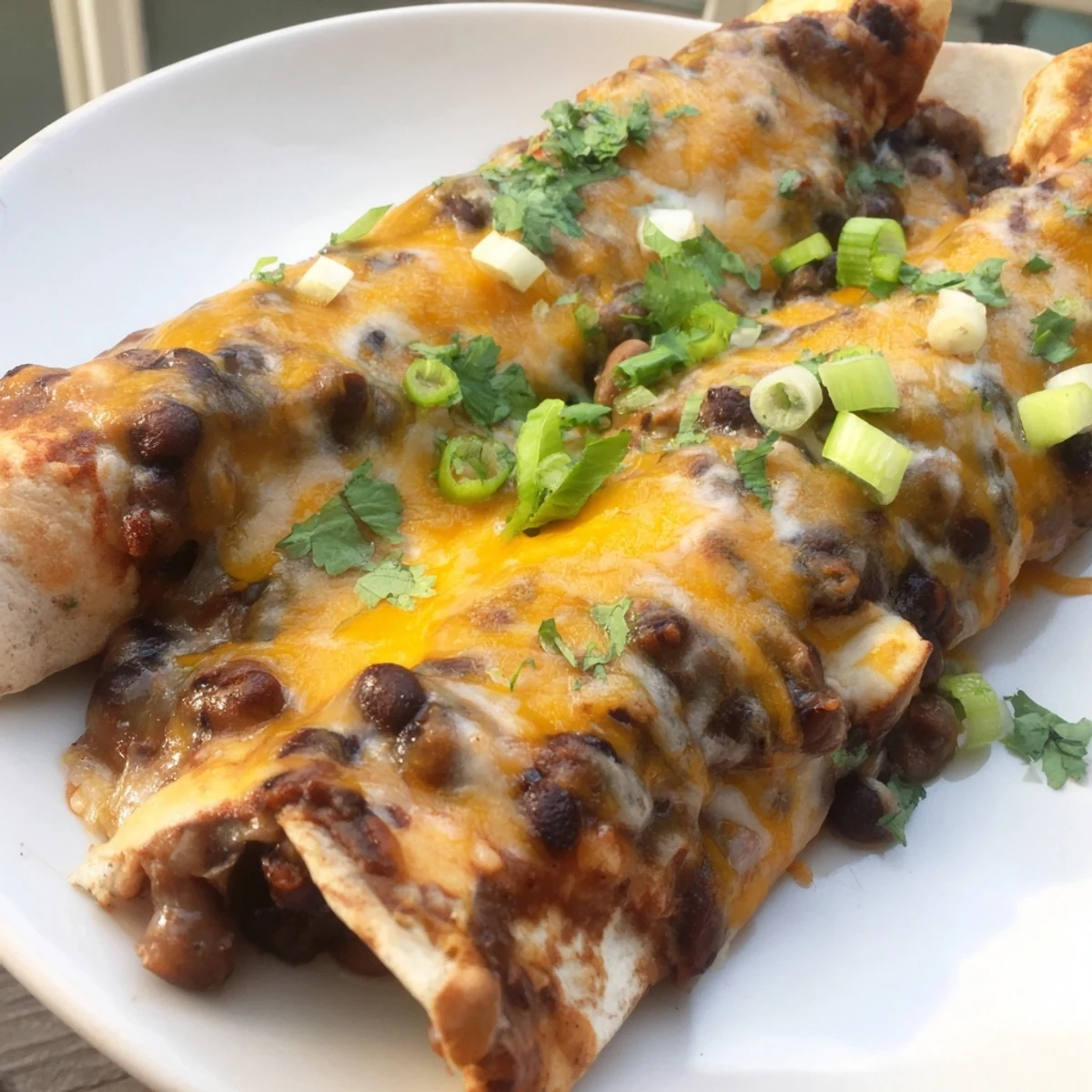 Mounds of melted cheese topping bubbly, saucy Cheesy Bean Enchiladas, a hearty Mexican meal.