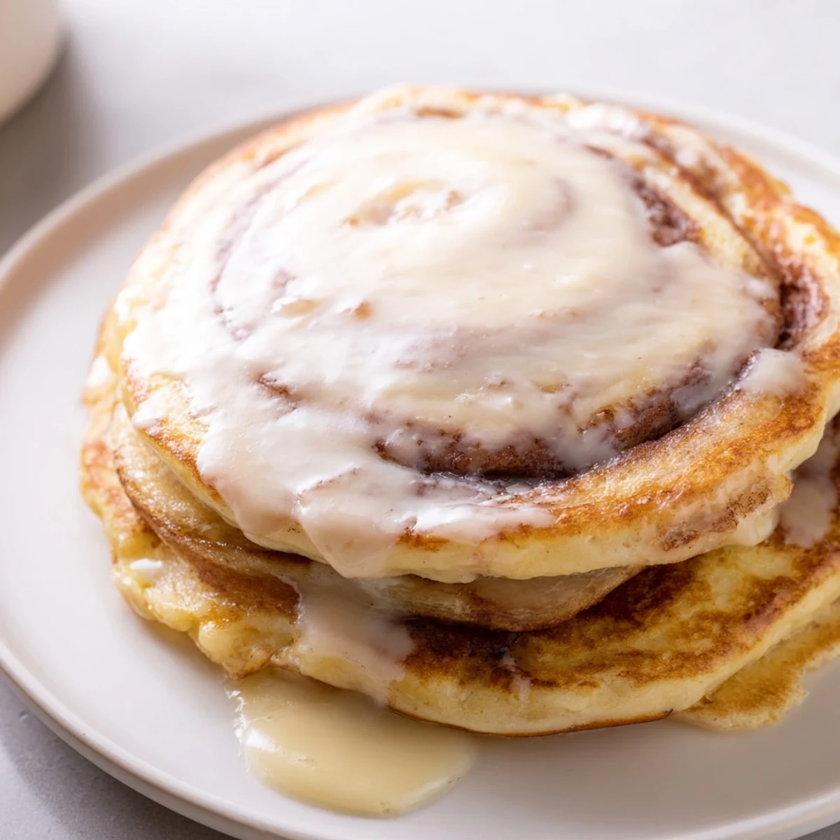Homemade Cinnamon Roll Pancakes presented, showcasing the creamy glaze and a delicious aroma.
