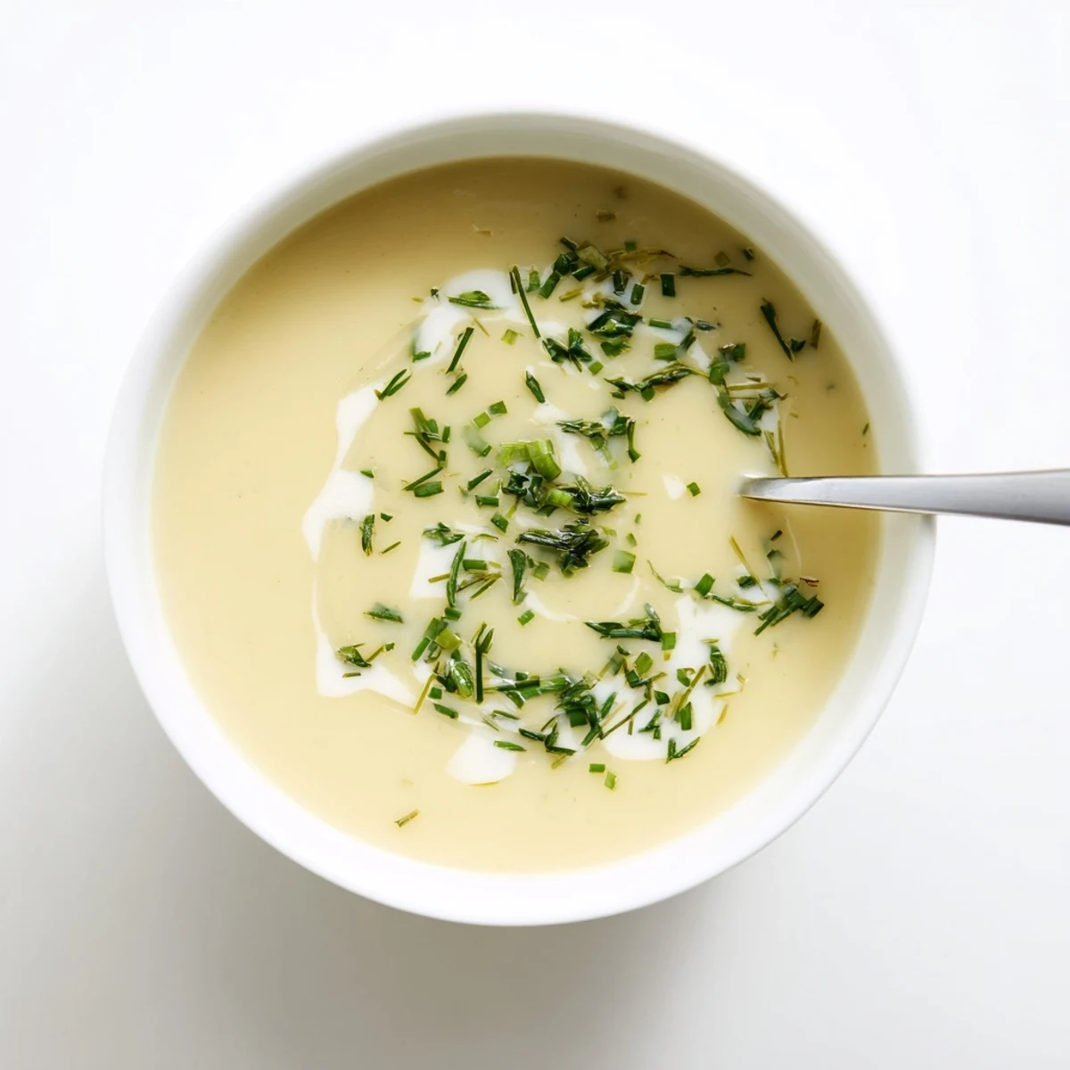 A warm bowl of creamy Parsnip and Herb Soup garnished with fresh chives and dill.  
