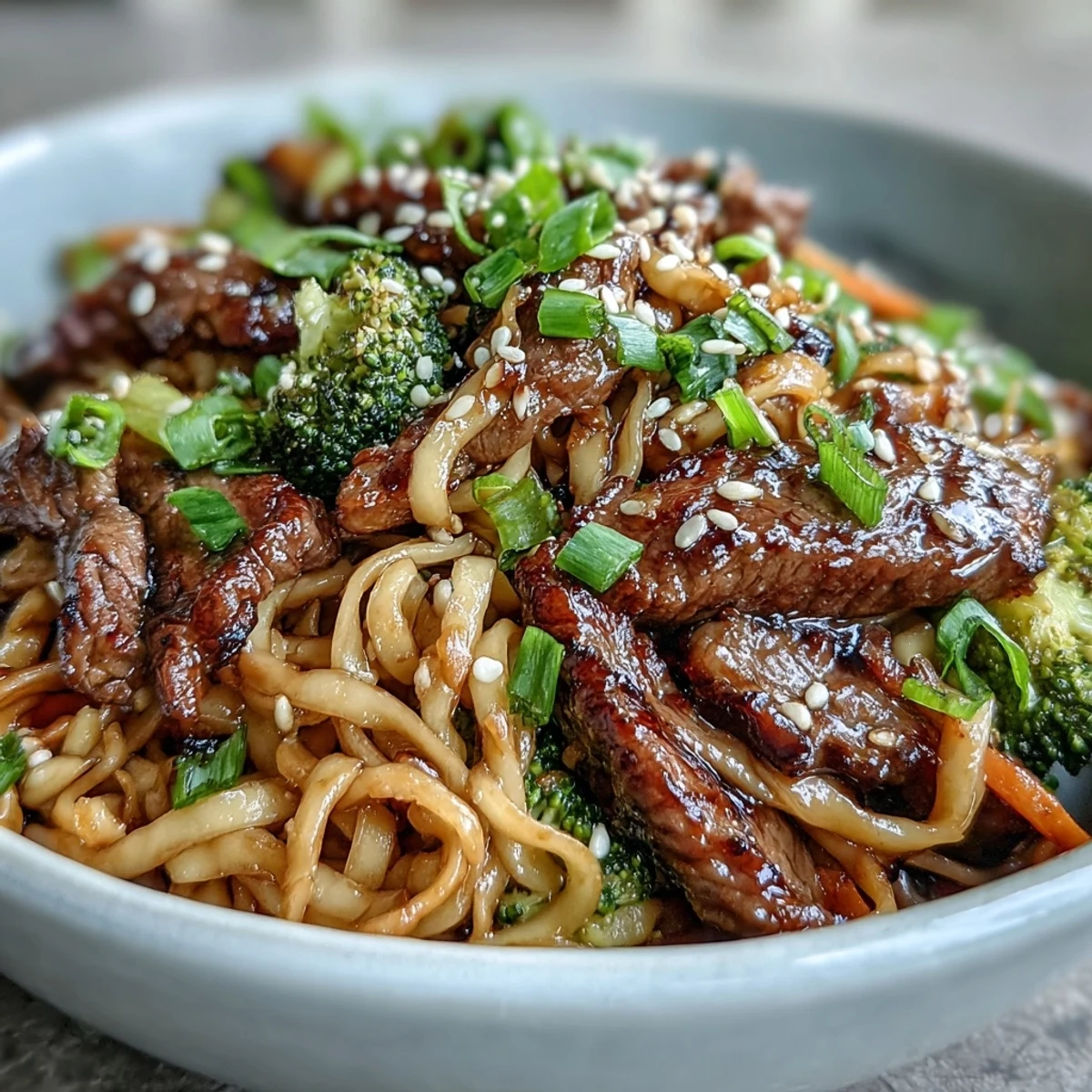 Golden-brown flank steak and vibrant broccoli, bell pepper, and carrot stir-fry are tossed with silky rice noodles in a glossy soy-ginger sauce, garnished with sesame seeds.