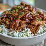Serving suggestion for Pulled Pork Bowl: a hearty, gluten-free meal with juicy shredded pork, cilantro garnish, and a colorful mix of red and green cabbage slaw.