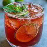 Chilled guava juice with sparkling water in a tall glass over ice, garnished with fresh mint.