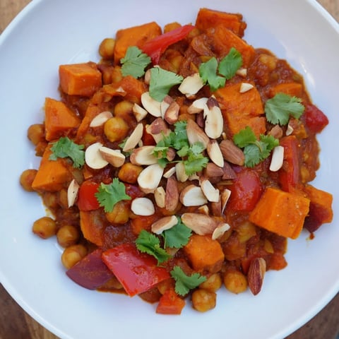 Steaming Moroccan Chickpea & Sweet Potato Tagine, a vibrant, spiced stew ready to serve with fresh herbs.