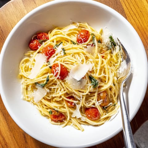 Steaming plate of Lazy-Girl Pasta, featuring juicy red tomatoes and grated Parmesan cheese.