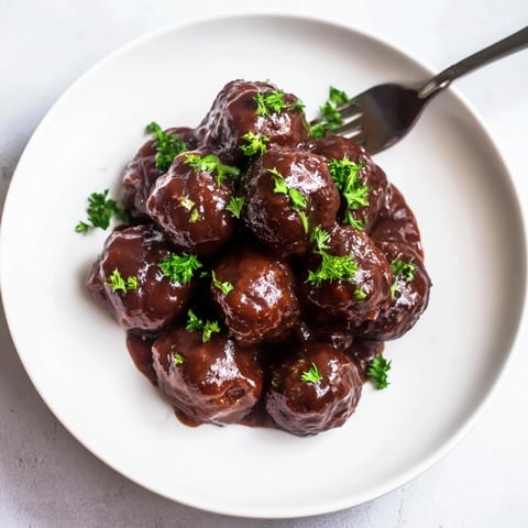 Golden, glossy cherry BBQ meatballs simmer in a slow cooker, ready for serving as a hearty appetizer.