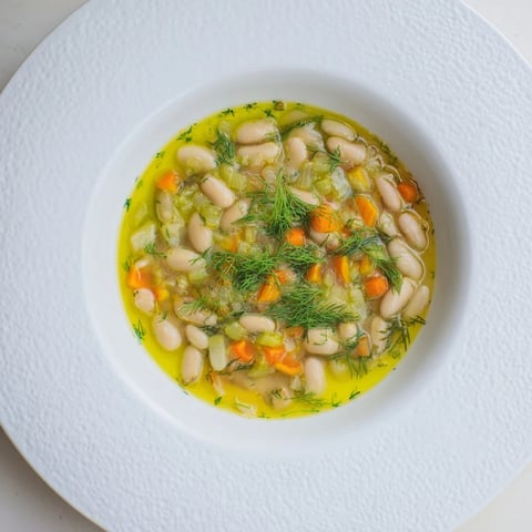A steaming bowl of Simple White Bean and Fennel Soup, garnished with fennel fronds.