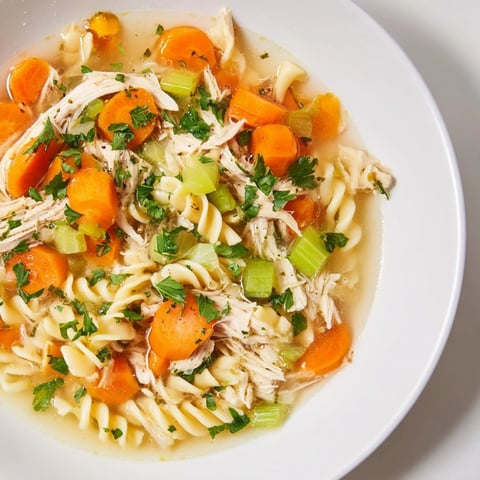 Steaming bowl of Crockpot Chicken Noodle Soup: a comforting American classic with tender chicken and noodles.