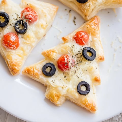 Golden, flaky Puff Pastry Christmas Tree Pizza Bites topped with melted cheese and vibrant tomatoes.