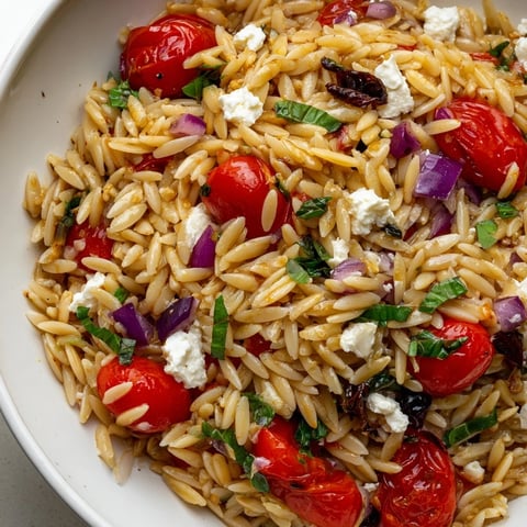 Vibrant Tomato Feta Orzo pasta salad with crumbled feta and fresh basil ready to serve.