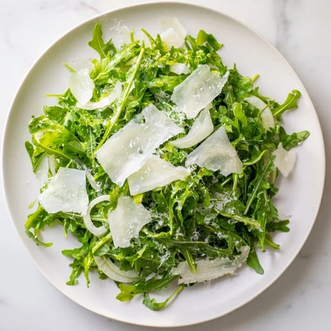 Fresh arugula salad with a bright lemon dressing, Parmesan cheese, perfect for a light lunch.