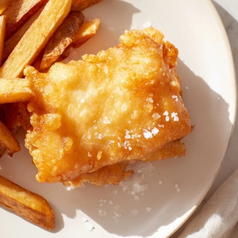 Golden, crispy British Fish & Chips, imagine flaky white fish with perfectly fried, thick chips and malt vinegar.