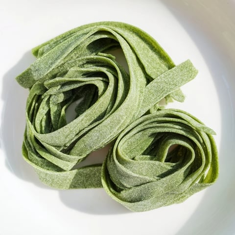 Vibrant green spinach pasta dough, ready to be rolled and cut into fresh pasta shapes.