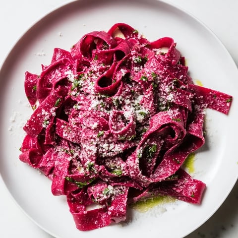 Steaming plate of Beet Noodle Pasta with fresh herbs, ready to be enjoyed as a vibrant, colorful meal.