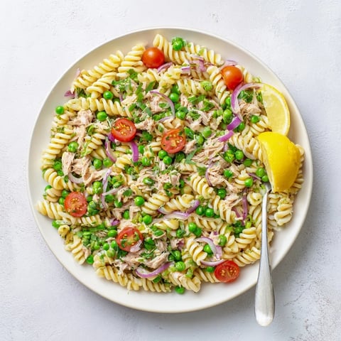 Close-up of Lemony Tuna Pasta Salad with bright lemon zest, fresh dill, and green peas tossed with al dente fusilli pasta.  