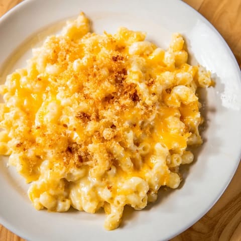 A close-up of baked Mac & Cheese shows a generous portion of cheesy goodness ready to eat.