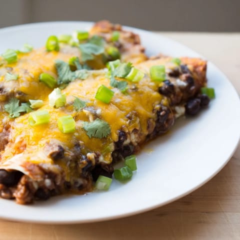 Warm, flavorful Cheesy Bean Enchiladas, filled with seasoned beans, ready for a delicious dinner.