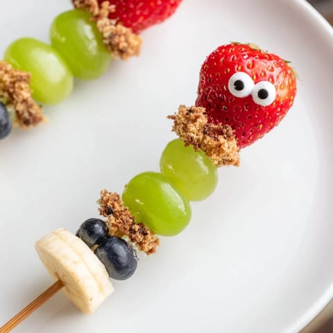 Sweet Caterpillar Fruit Skewer Track with juicy grapes, strawberries, and blueberries trailing along a chocolate crumb path for kids.