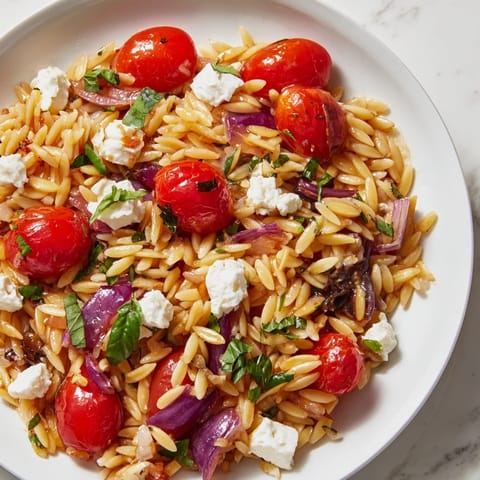 A bright bowl of Tomato Feta Orzo, a Mediterranean delight, featuring bursting cherry tomatoes.