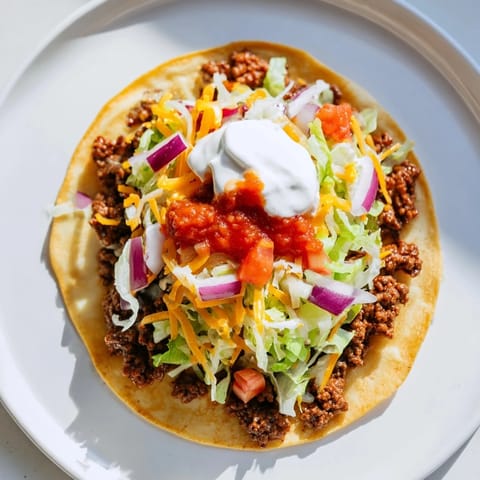 Close-up of freshly cooked Crispy Smash Tacos, with crispy beef and colorful, fresh toppings over tortillas.