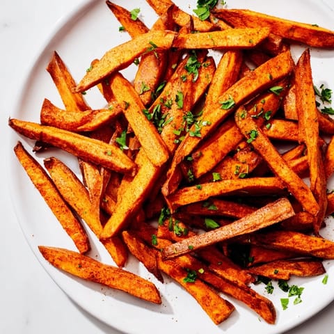 Air-fried Cajun spiced sweet potato fries, with a vibrant, flavorful spice coating and fresh parsley garnish.