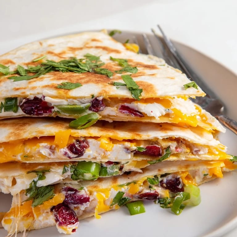 Colorful cranberry jalapeño dip quesadillas garnished with fresh cilantro and lime wedges.