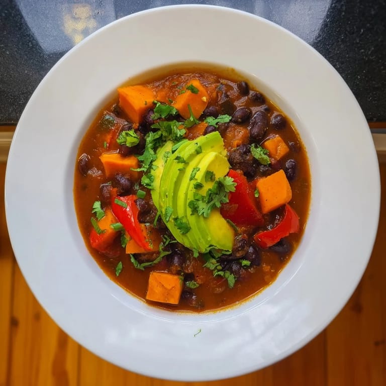 Aromatic Sweet Potato & Black Bean Chili simmering with vegetables and savory spices in a pot.