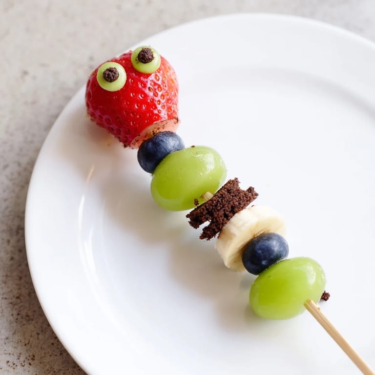 Colorful Caterpillar Fruit Skewer Track: fresh fruit skewers arranged like playful caterpillars on a chocolate cookie track.