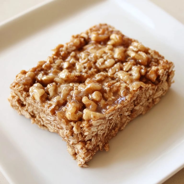 Warm, chewy Maple Cinnamon Oatmeal Bars showcasing a delightful texture flecked with nuts and raisins.
