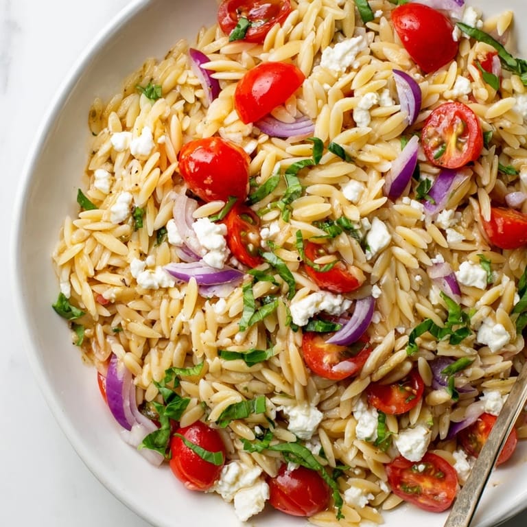 Freshly made Tomato Feta Orzo: orzo pasta tossed with tomatoes, feta and herbs, a healthy meal.
