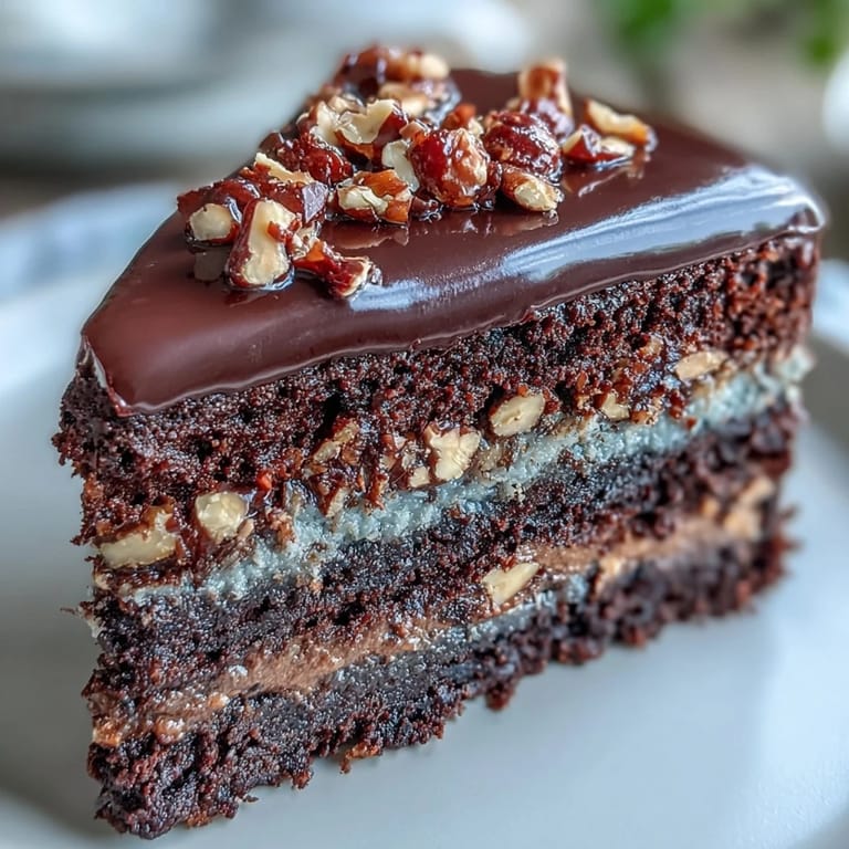 This decadent chocolate celebration cake features glossy ganache and toasted hazelnut praline, perfect for birthdays or special gatherings.  