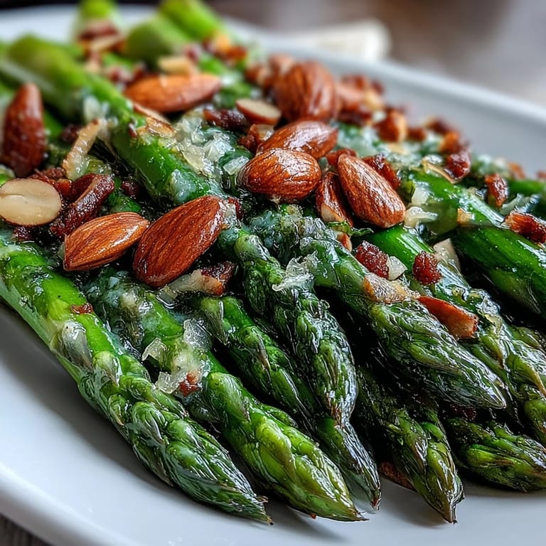 Tender asparagus spears sautéed in rich lemon butter, garnished with crunchy toasted almonds for a delightful spring side dish.