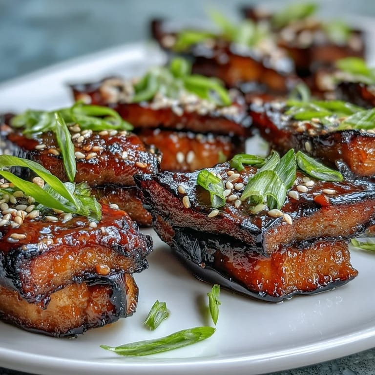 Warm miso glazed eggplant halves, topped with sesame seeds and green onions, served fresh from the oven.