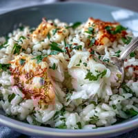 A close-up of Smoked Haddock Risotto in a wide bowl, garnished with fresh parsley and lemon zest.