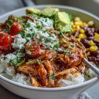 Colorful salsa chicken bowls with tender shredded chicken, black beans, and corn over rice, topped with fresh avocado and tomatoes.